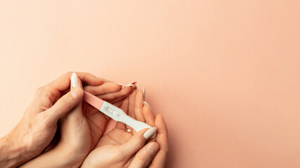 Pregnancy test positive. Female hand hold positive pregnant test with silk ribbon on pink background. Medical healthcare gynecological, pregnancy fertility maternity people concept. - obrazy, fototapety, plakaty