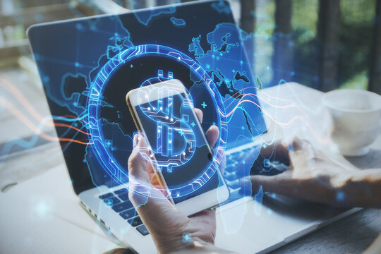 Close up of hands using laptop and smartphone with abstract glowing blue dollar sign and map with charts on blurry background. Currency, trade and digital market concept. Double exposure.