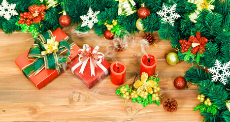 Fototapeta na wymiar Closeup studio shot of Red paper wrapped present gift boxes with ribbon bowtie candles and wreath placed on wood floor decorated with Christmas eve pine tree with sphere balls snowflakes hanging