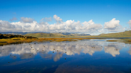 Beautiful clouds in blue sky with reflection in calm water in the morning lake.