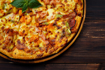 Closeup top view studio shot of Italian delicious tasty pepperoni pizza on white plate with oregano and red chilli power spices in wooden spoons decorated with basil and sliced tomatoes on old table