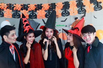 Portrait shot group of Asian young happy male and female friends in Halloween witch sorcerer ghost...