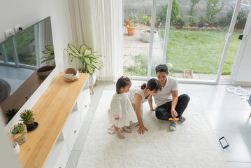 Overhead shot of a beautiful Asian family sitting on the living room carpet playing a game. 