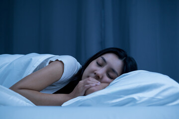 Beautiful asian woman lying in the bed at night. Young woman sleeping well in comfortable cozy fresh bed on soft pillow white linen. Health and rest concept.
