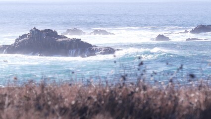 Rocky craggy ocean beach. Big waves crashing on bare cliff, blue water splashing, sea foam. Power of nature near Big Sur, 17-mile drive. Dramatic seascape. Point Lobos, Monterey, California coast, USA