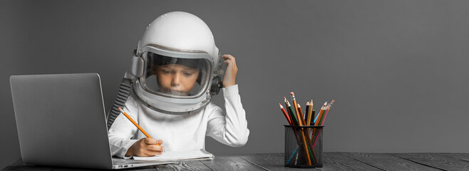 the child studies remotely at school, wearing an astronaut's helmet. back to school