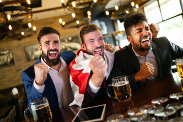 Men fans screaming and watching football on TV and drink beer in a pub