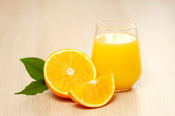 Orange juice in a glass with orange slices and a green leaf