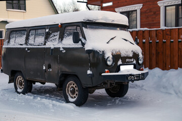 Snow-covered car in parking lot near houses