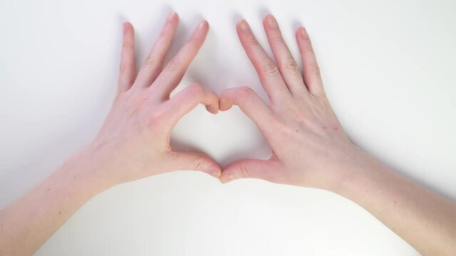 Top view of Caucasian female hands gestures. Right and left. Heart or fuck gesture. Show two fingers. Symbols and directions. Finger movements on a white table. Thumbs up and class.