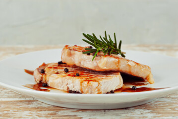 Pieces of meat grilled. Steak with rosemary and pepper in a white plate. Meat dish close up.