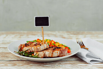 Pieces of meat grilled. Steak with vegetables in a white plate. Salad of corn, carrots and green peas near the steak. Copy space and free space for text near the plate. Plate for inscriptions on meat.