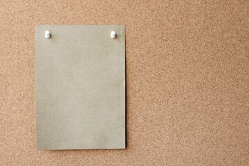 Blank Brown paper note with pin on corkboard. With copy space for ideas, reminders, appointments,...