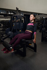 Fototapeta na wymiar Young female athlete training her legs in the gym