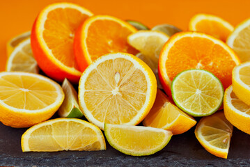 Naklejka na ściany i meble Oranges, lemons and limes cut into slices. Citrus vegetables on an orange background. Preparing vegetables for juice and cocktails.