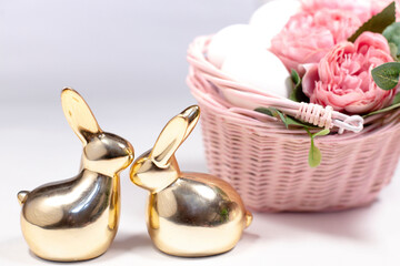 two golden rabbits behind white background with flowers