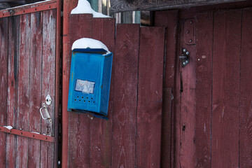 Blue mailbox on brown fence on winter day