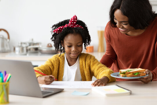 Caring Black Mom Bringing Snacks To Daughter Study With Laptop At Home