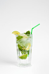 Green cocktail on a white background. Alcoholic mojito with ice close up. Lime, mint and straw in a cocktail. Copy space and wine place for text near the glass.