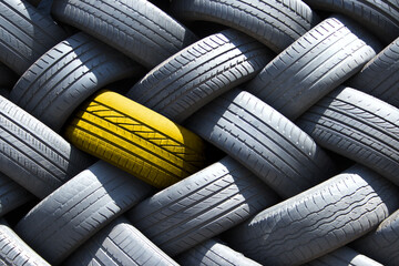 Single yellow tyre in a stack of tires