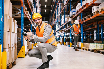 A happy supervisor approves order while holding bar code scanner in hands in storage.