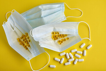 Medical masks and pills on a yellow background