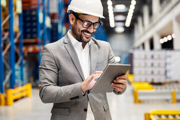 A supervisor in distribution center scrolling and smiling at the tablet.