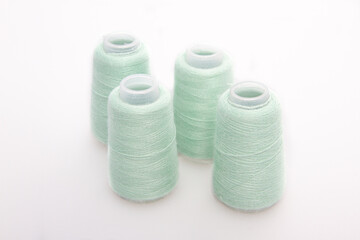 Fototapeta na wymiar Green spool of thread isolated on white background. Skein of woolen threads. Yarn for knitting. Materials for sewing machine. Coil.