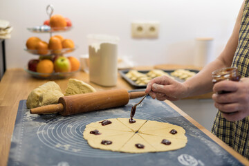 Female hand puts a plum filling on the cake