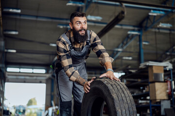 Obraz na płótnie Canvas Auto-mechanic in a workshop with tire.