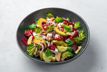 Healthy vegetarian vegetable salad with beetroot, avocado and feta seasoned with flax and sesame seeds on a gray background.
