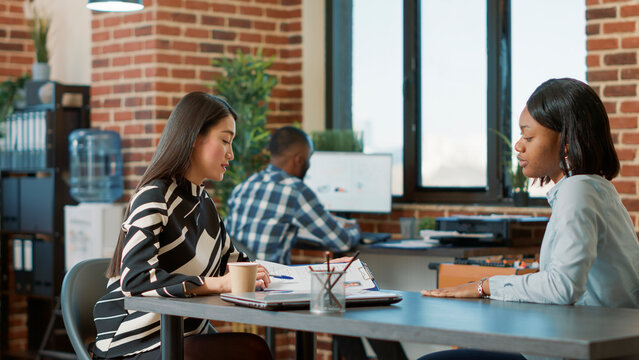 Female candidate greeting HR recruiter at job interview in company office. Employee reading cv information and interviewing work applicant, discussing about company recruitment.