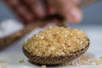 Brown sugar on spoon wood.