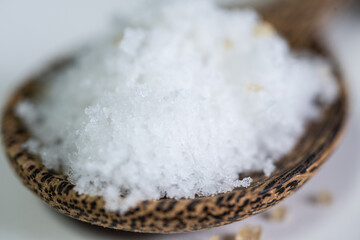 White salt on spoon wood.
