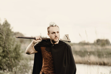 A young man with an interesting depicts a Viking with an ax in an unreliable stylized modern costume