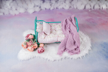 Fototapeta na wymiar Newborn baby girl bed with pink flowers in a photo studio