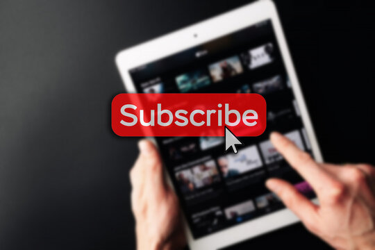 Subscription service. Online video red subscribe button. Internet service on laptop digital tablet blured technology background. Streaming video. Communication network.