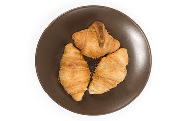 Top view of small baked croissants on a brown dish