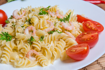 Cooked spiral pasta with shrimps, cheese, cherry tomatoes close-up