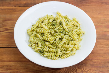 Spiral pasta with sauce pesto on dish on rustic table