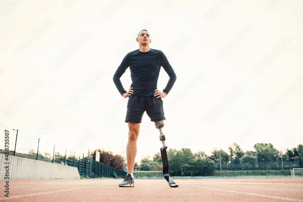 Poster A handicapped sportsman standing at stadium and taking a break.