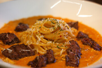 Rose pasta and steak slices are served together.