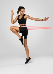 Fototapeta na wymiar Sportswoman exercising with resistance band. Female with working out with elastic band on white background