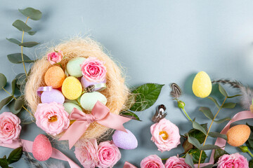 Happy Easter concept with easter eggs and spring flowers on a blue background. Easter web banner with copy space for text. Flat lay.