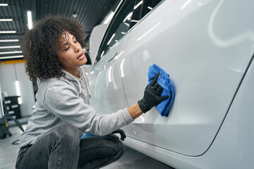 Worker wiping down car door outer panel with absorbent cloth