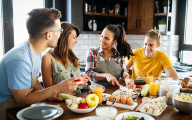 Beautiful happy people, friends is smiling while cooking together in the kitchen