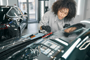 Concentrated car mechanic affixing automotive equipment to windscreen