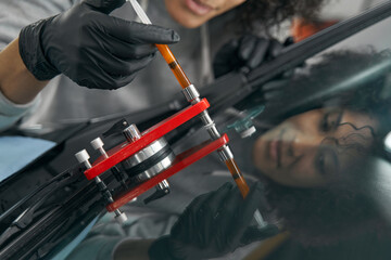 Experienced auto shop mechanic repairing scratched windshield