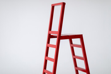 Red wooden staircase on a light background. Ladder. Garden tools. Lifting device. copy space.