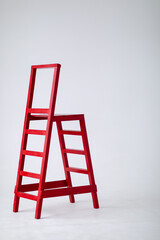 Red wooden staircase on a light background. Ladder. Garden tools. Lifting device. copy space.